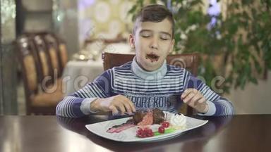 可爱的黑发小男孩喜欢吃巧克力甜点，脏嘴手在<strong>高档餐厅</strong>，舒适的氛围背景。